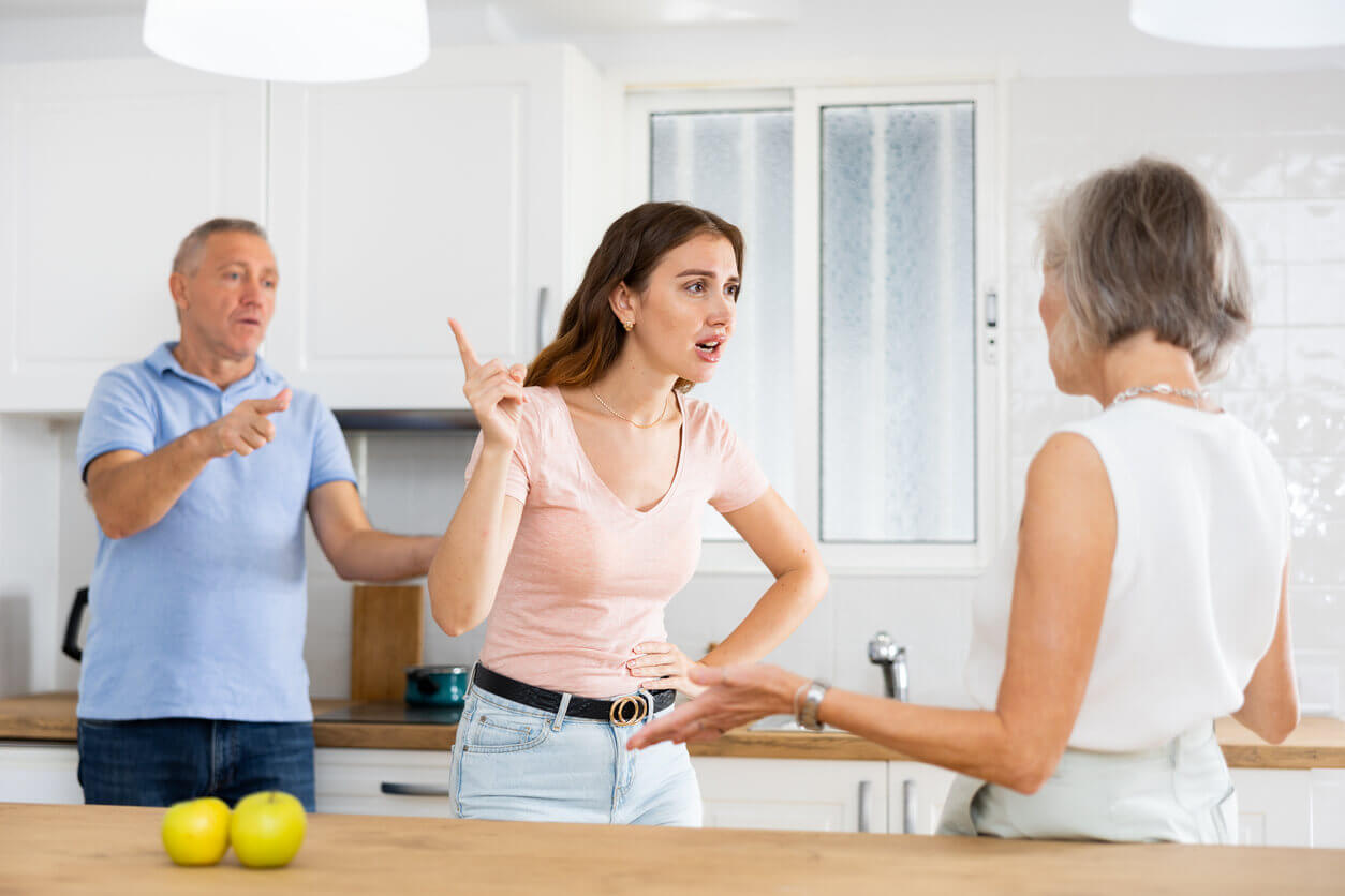 Elderly father tries to calm quarreled wife and daughter in home kitchen