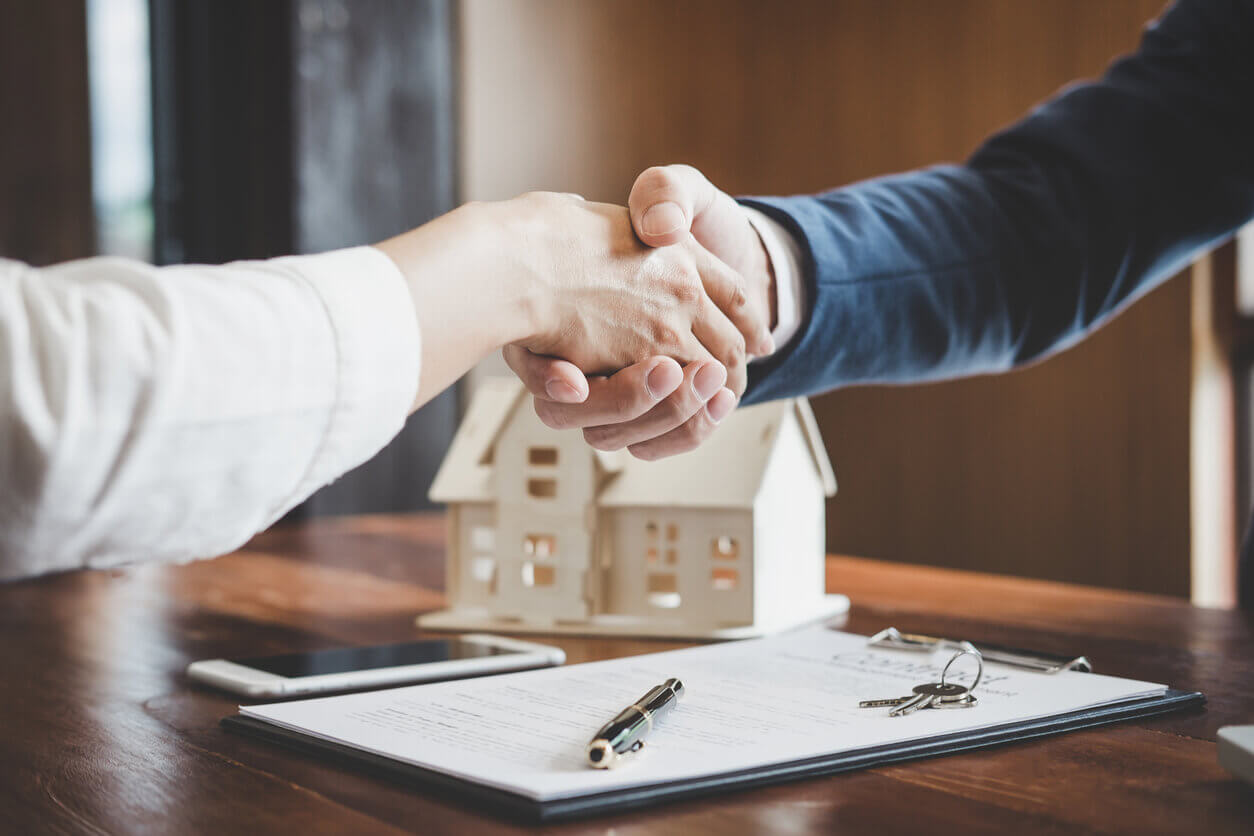 Real estate agent and customers shaking hands together celebrating finished contract